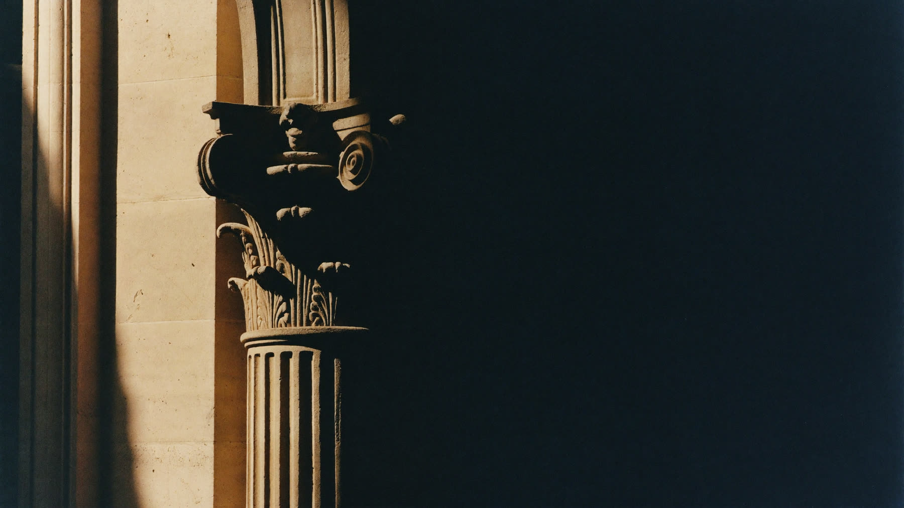 Raking light across a carved limestone column of a neoclassical facade