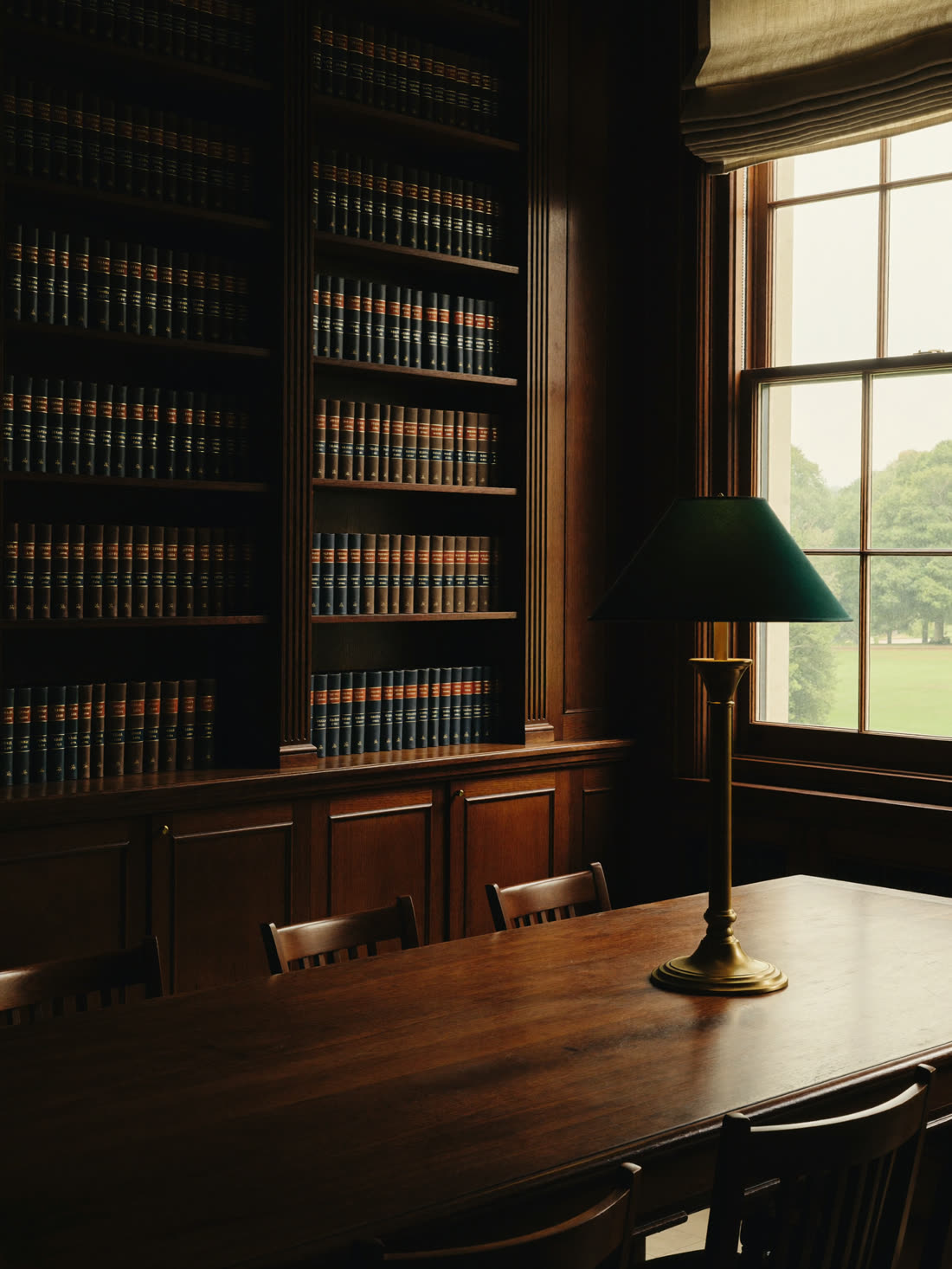 The firm's reading room — walnut shelves, leather-bound volumes, a single shaft of window light
